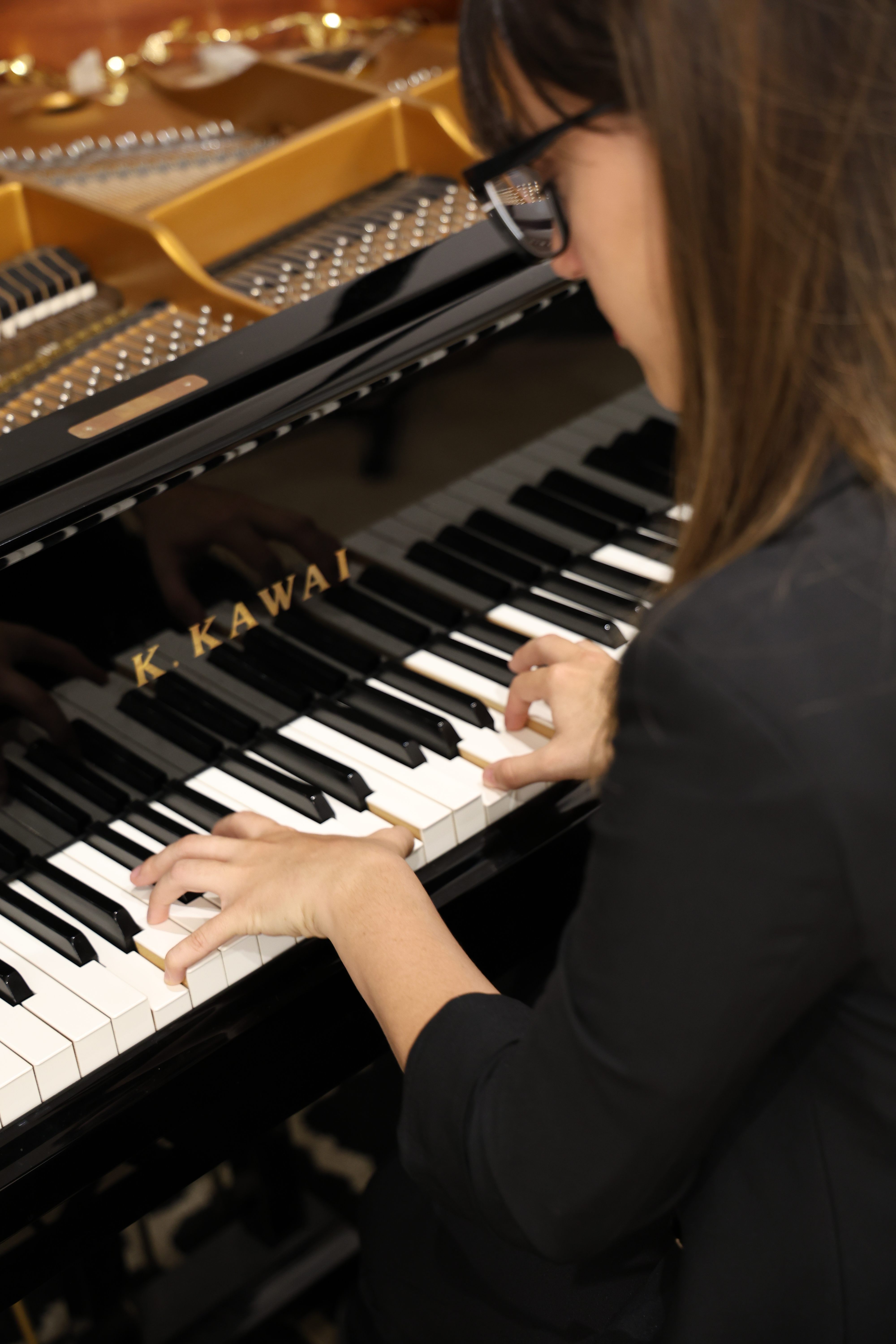 Detalle de manos tocando el piano de cola Kawai